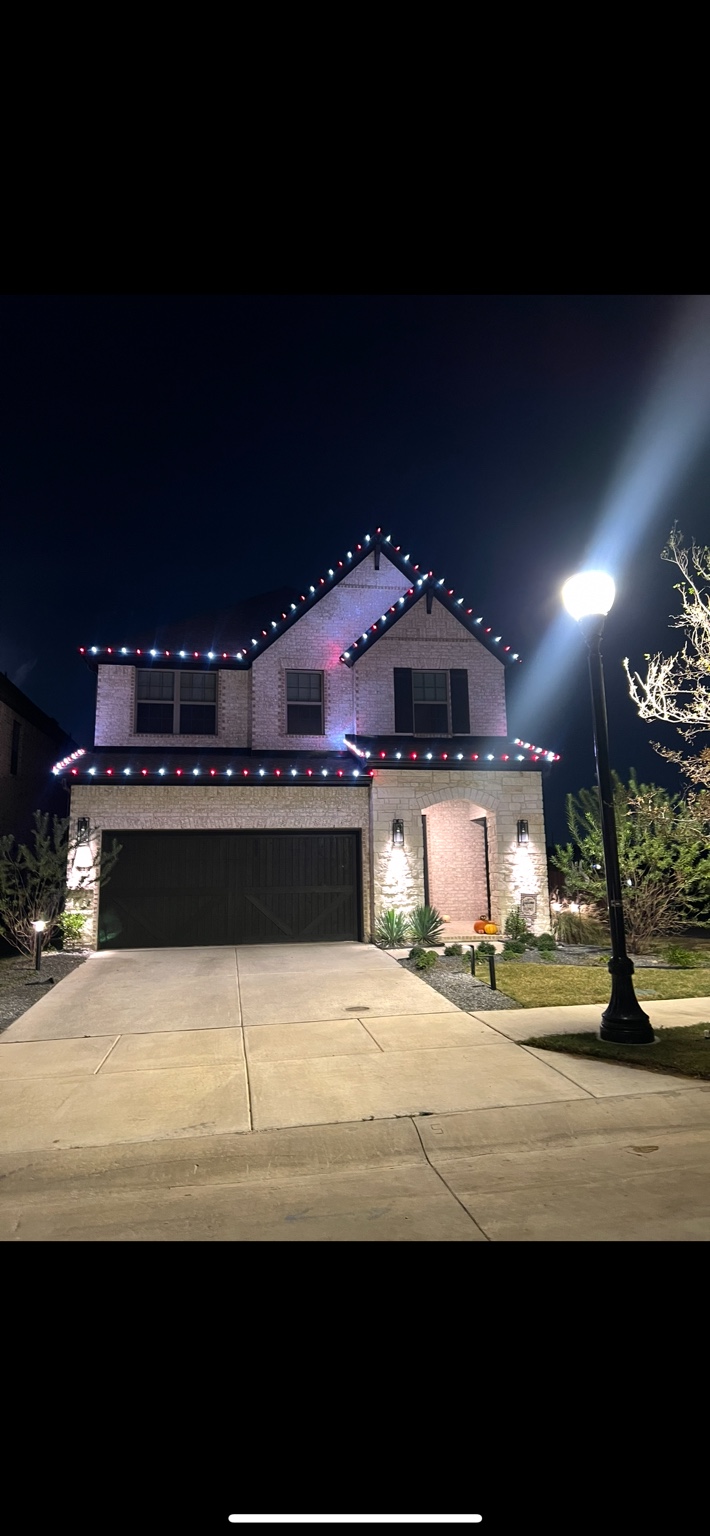 Two-story North Texas home with a red and white seasonal roofline lighting display